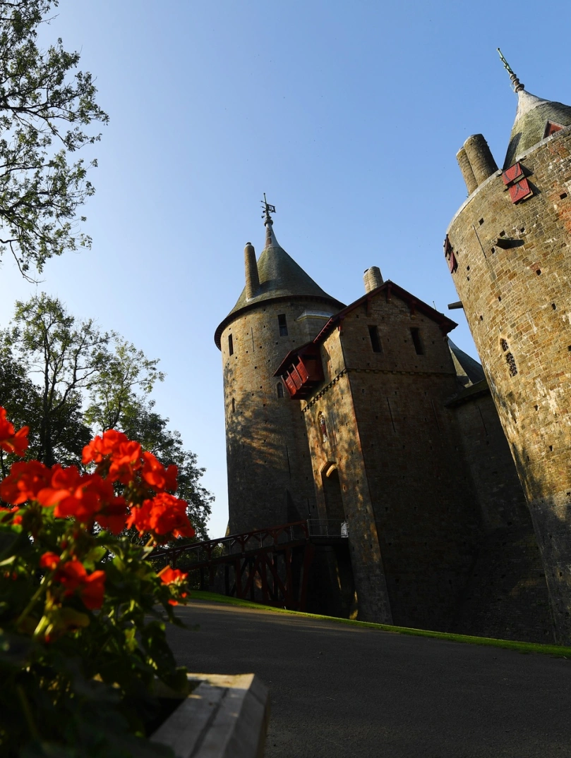 Flowers in bloom next to the path of a castle entrance.