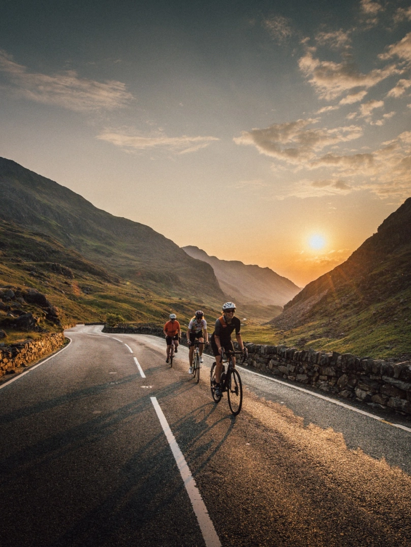 Group of cyclists on a mountain road with the sunsetting beyond.