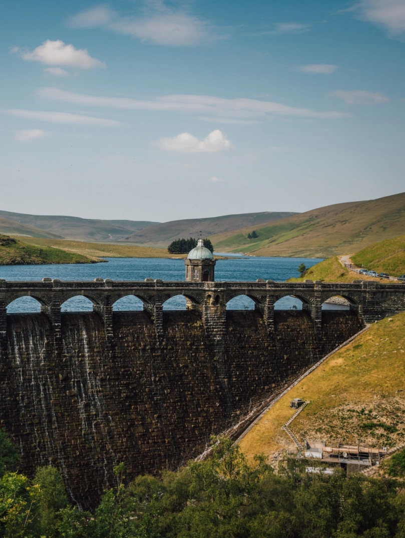 Aerial shot of a dam and a reservoir with mountainous scenery.