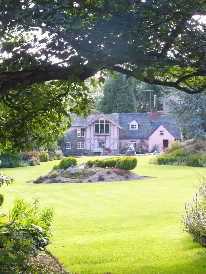 A house amongst a beautiful lawn and gardens.