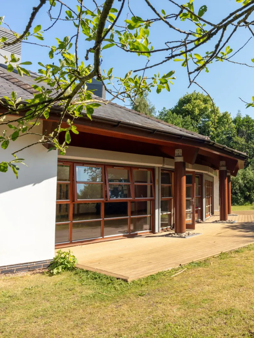 External shot of a conservatory surrounded by green trees.