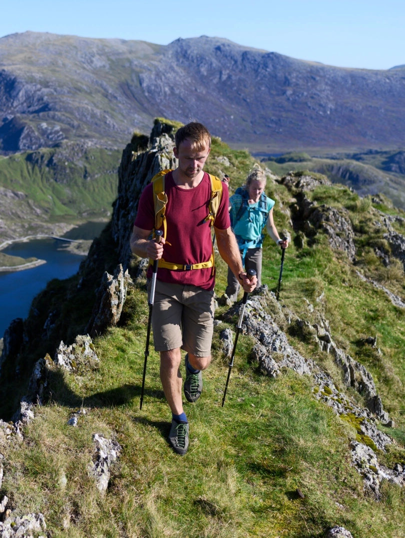 A couple walking on the top of a ridge with a lake below.