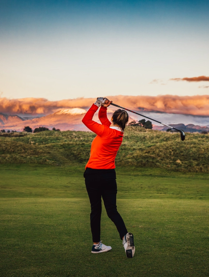 A golfer taking a shot with a castle in the foreground.