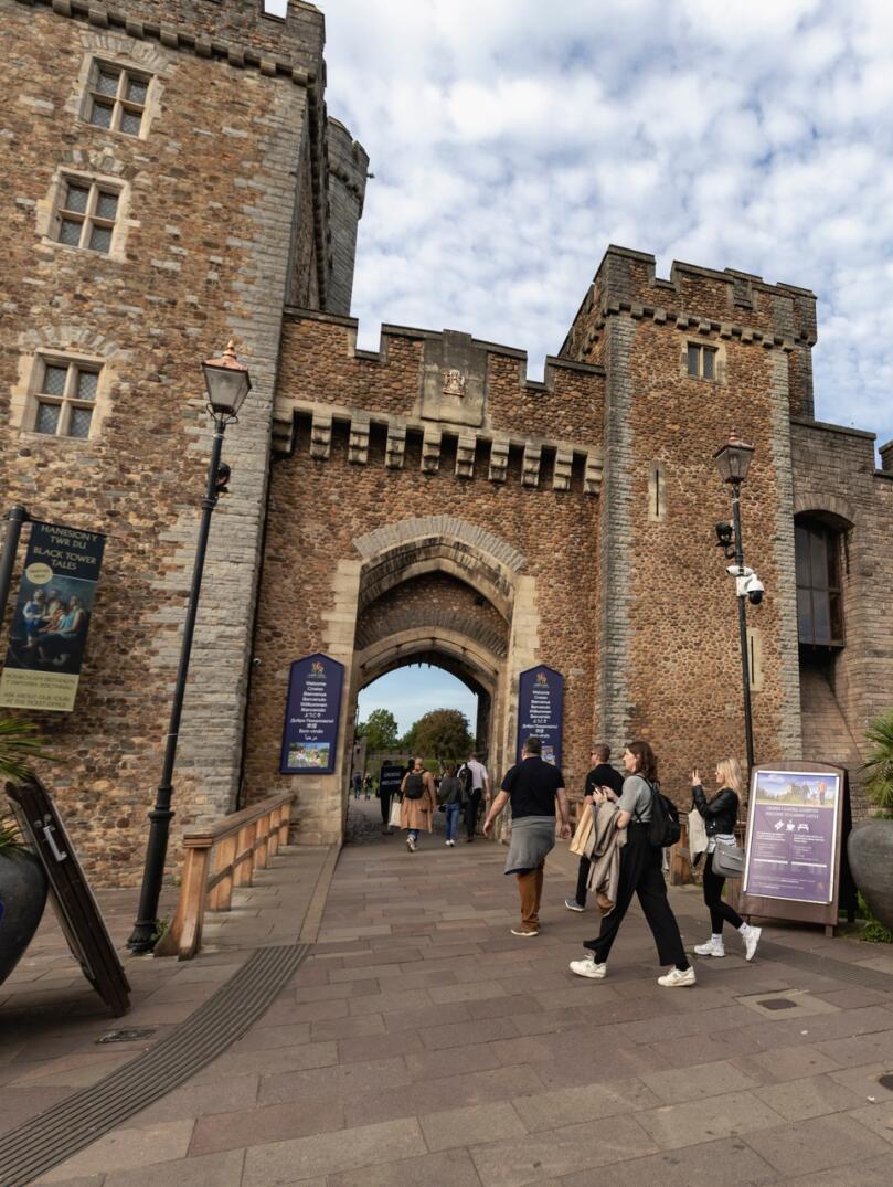 People walking into the entrance of a castle.