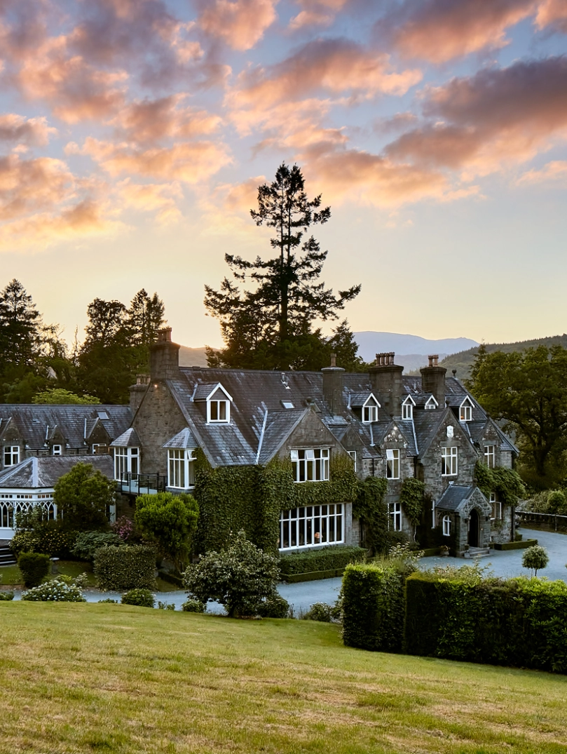 External shot of a hotel surrounded by greenery, under a dramatic sunset,