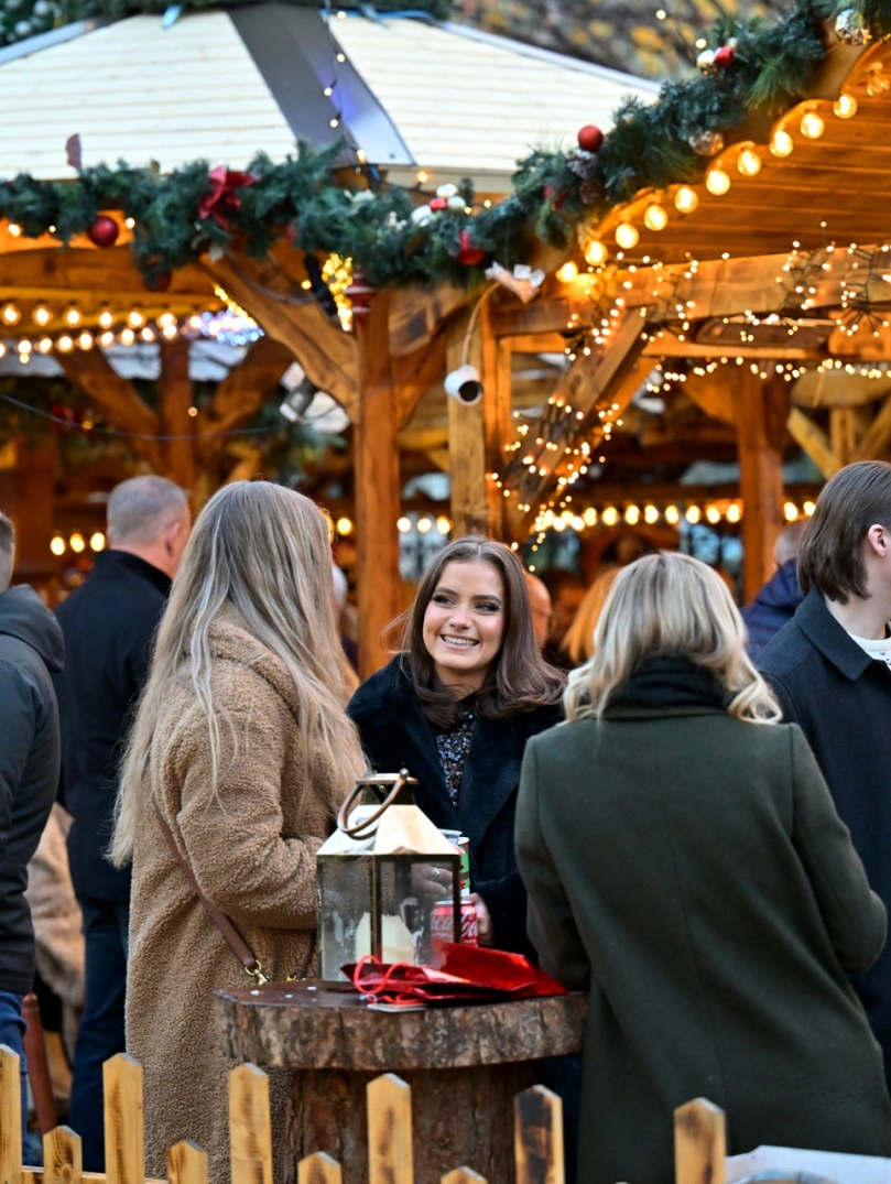 Group of ladies chatting and enjoying a drink at a Christmas market.