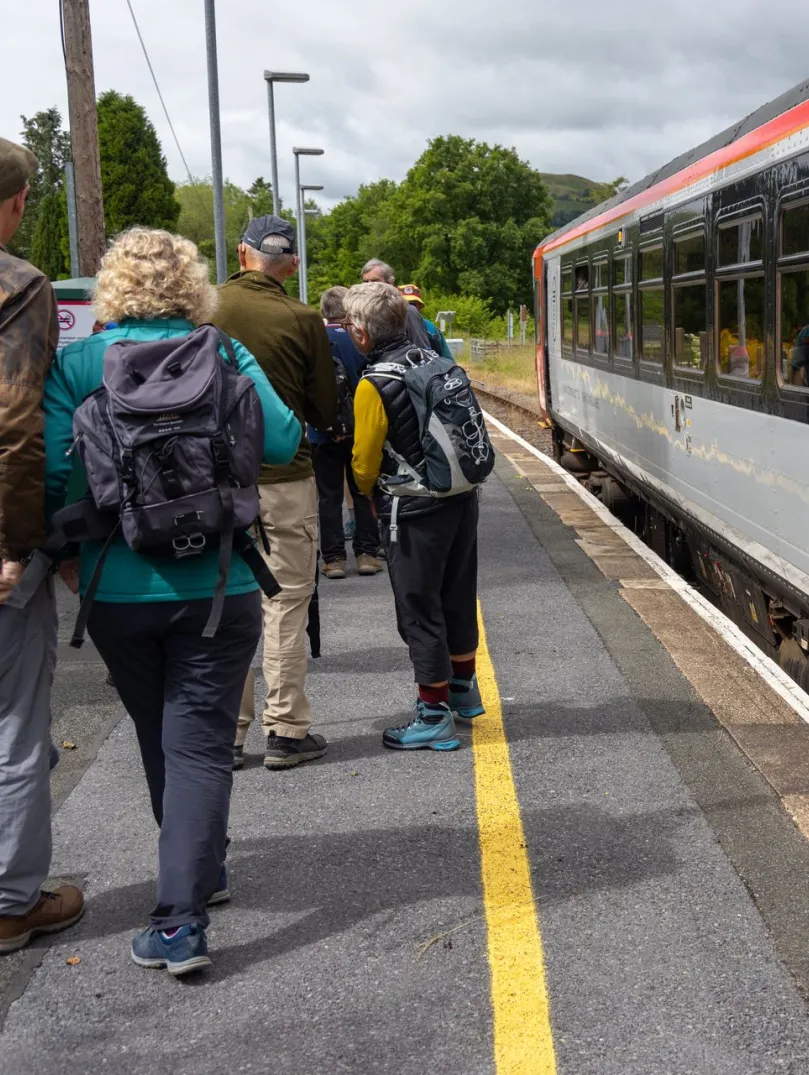 Walkers on a platform about to board a train.