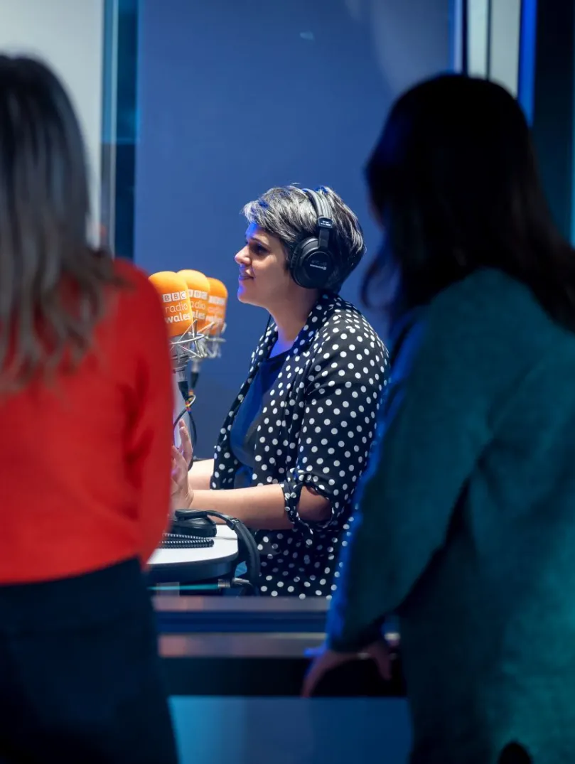 Group of people on a tour, looking through a glass screen at a presenter at work.