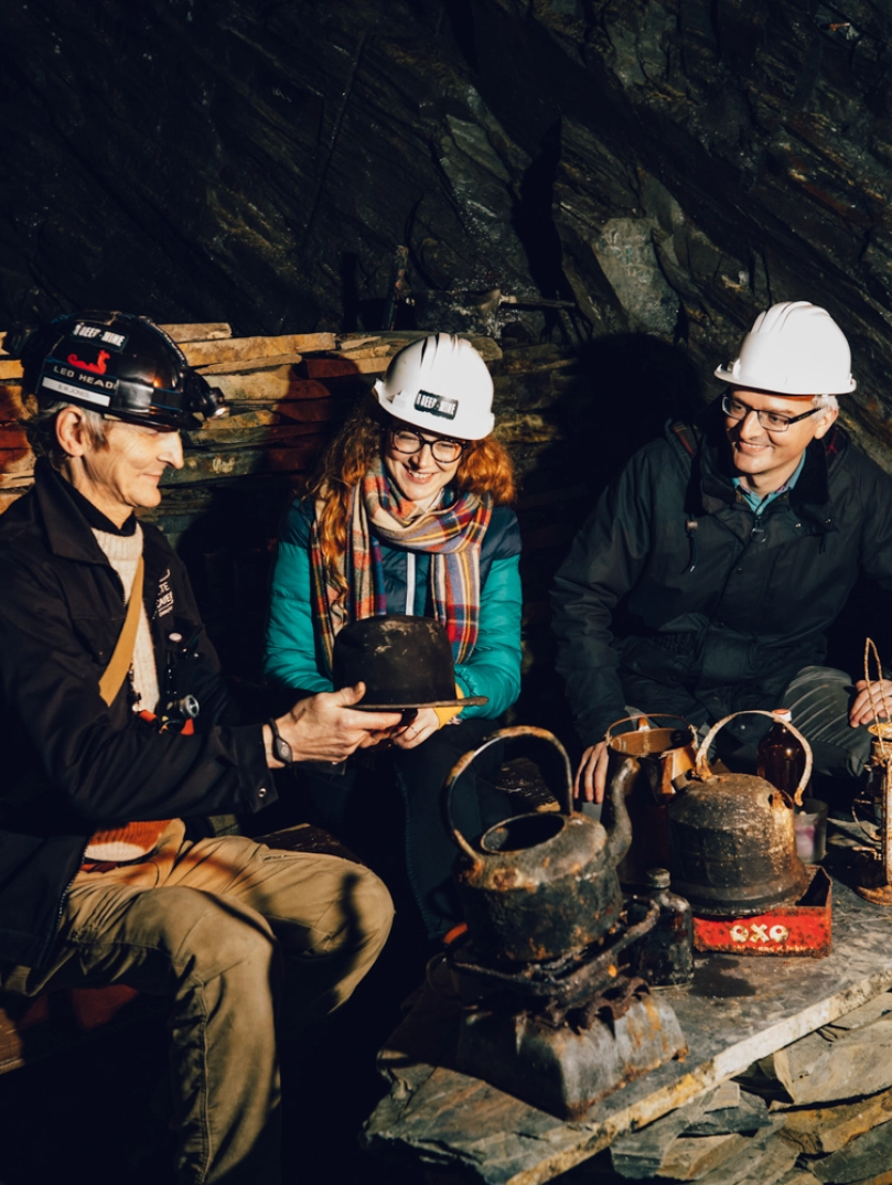 A couple looking at artefacts with a tour guide in an underground mine.