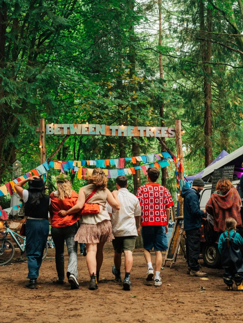Group of people heading toward a festival in a forest.