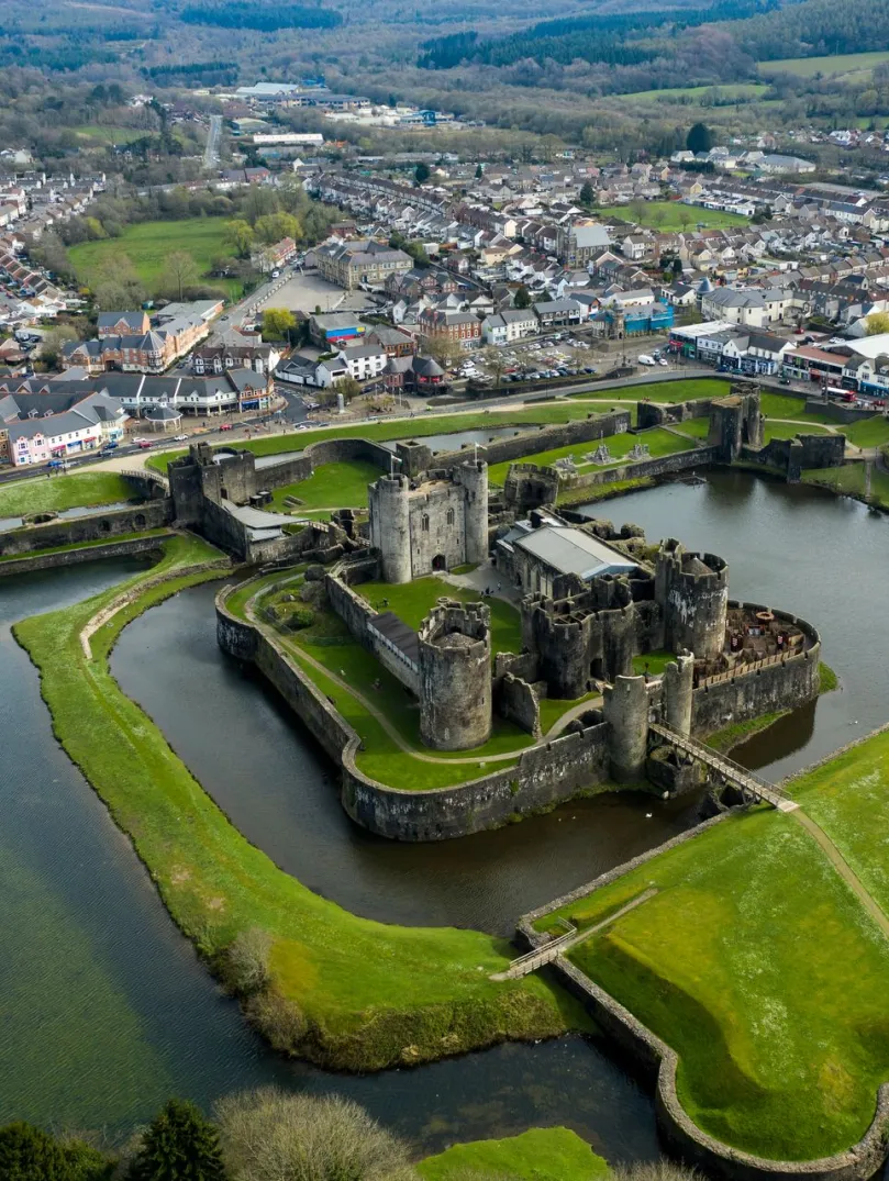 Aerial shot of a castle surrounded by a moat and green embankment.