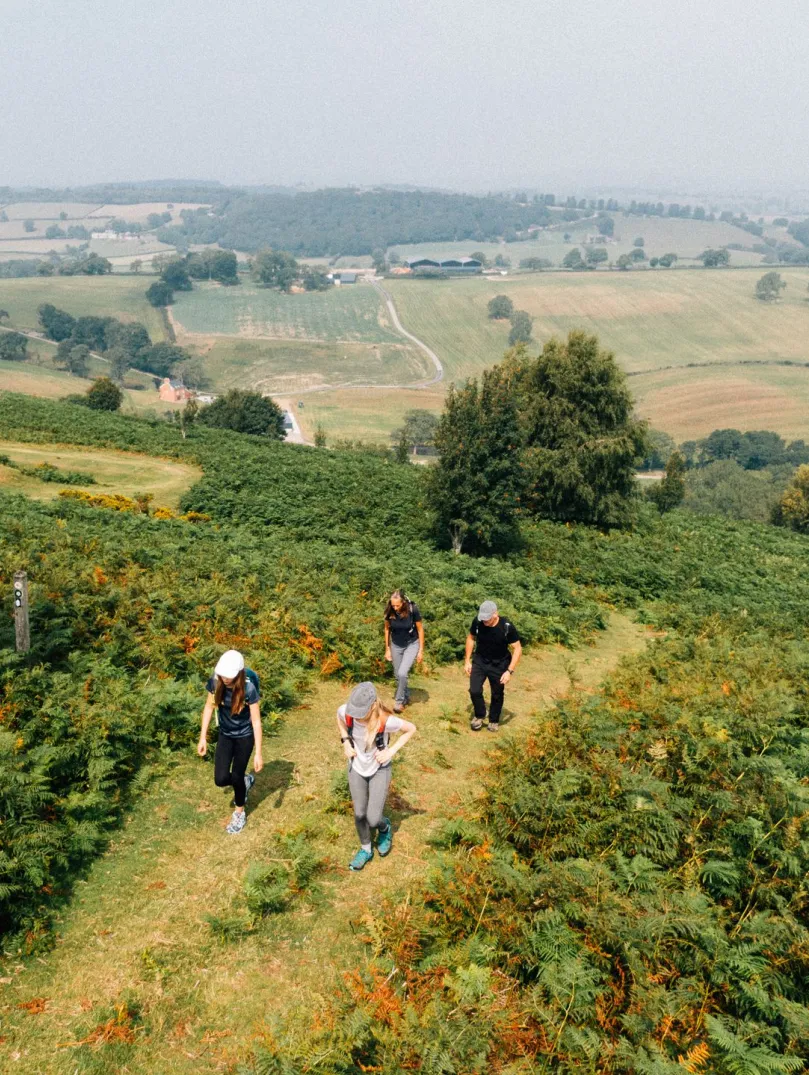 Group of walkers on a mountain footpath with scenic views beyond.
