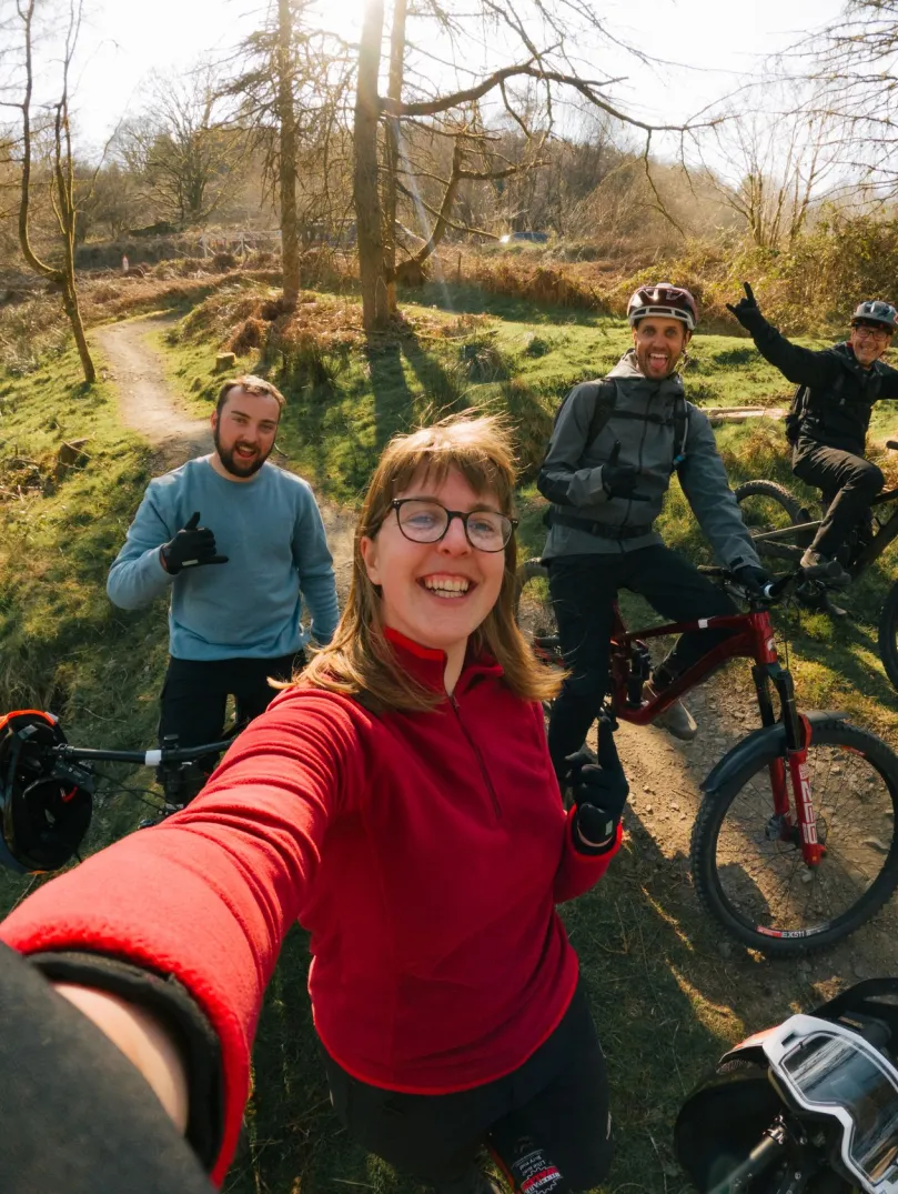 Group of people with their bikes in a bike park smiling at the camera.