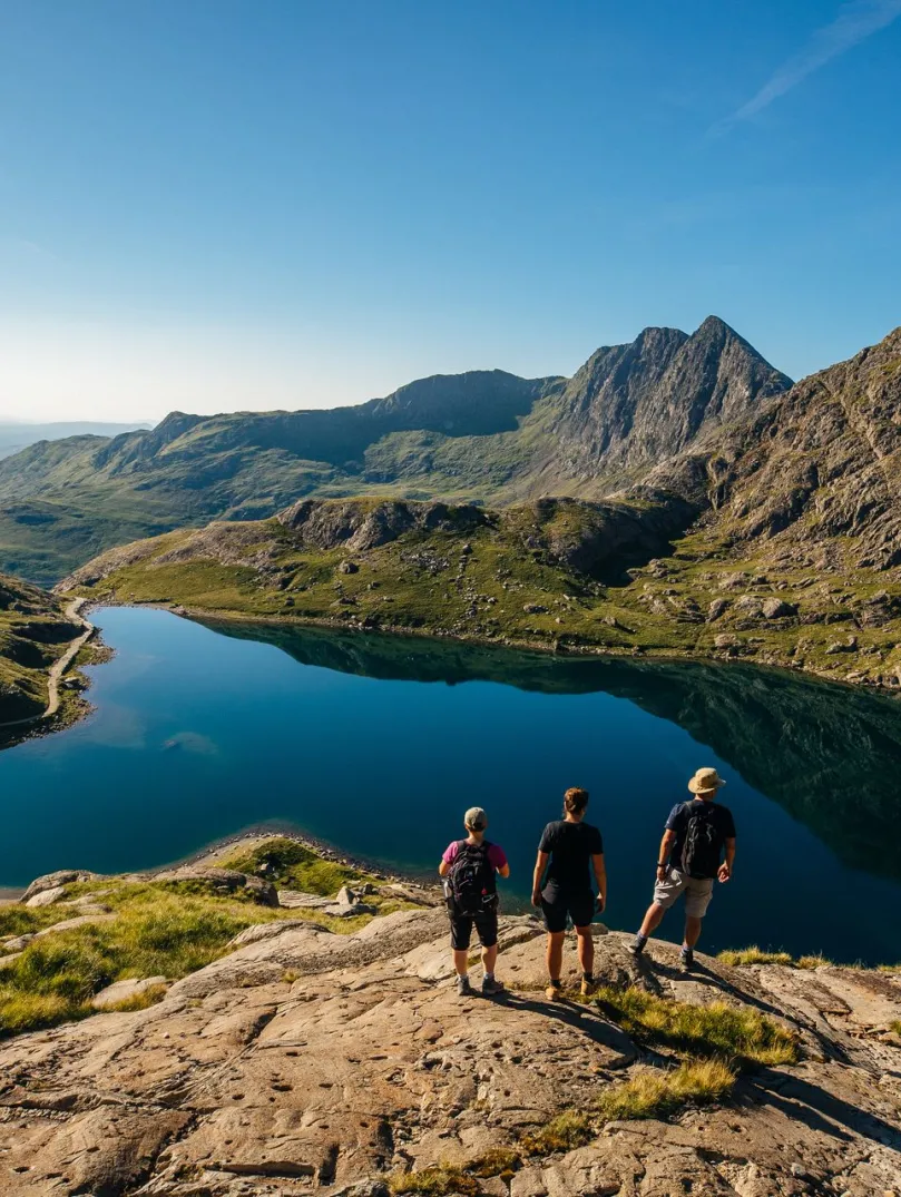 Group of walkers overlooking a lake on the top of a mountain.