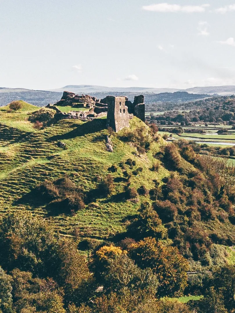 A castle on a hill with views alongside a river surrounded by countryside.