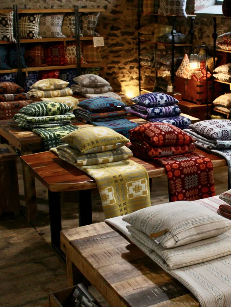 Woven blankets and cushions on display in a shop.