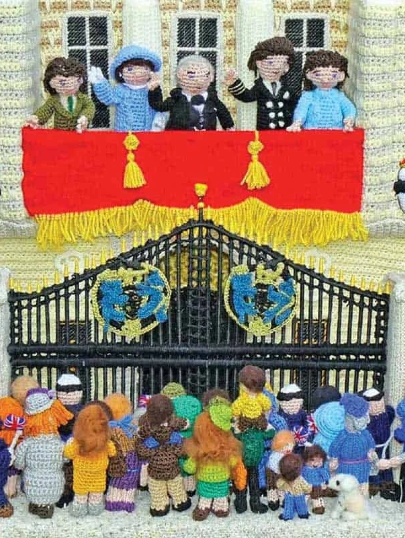 Knitted scene of the Royal Family on a balcony waving to crowds below.