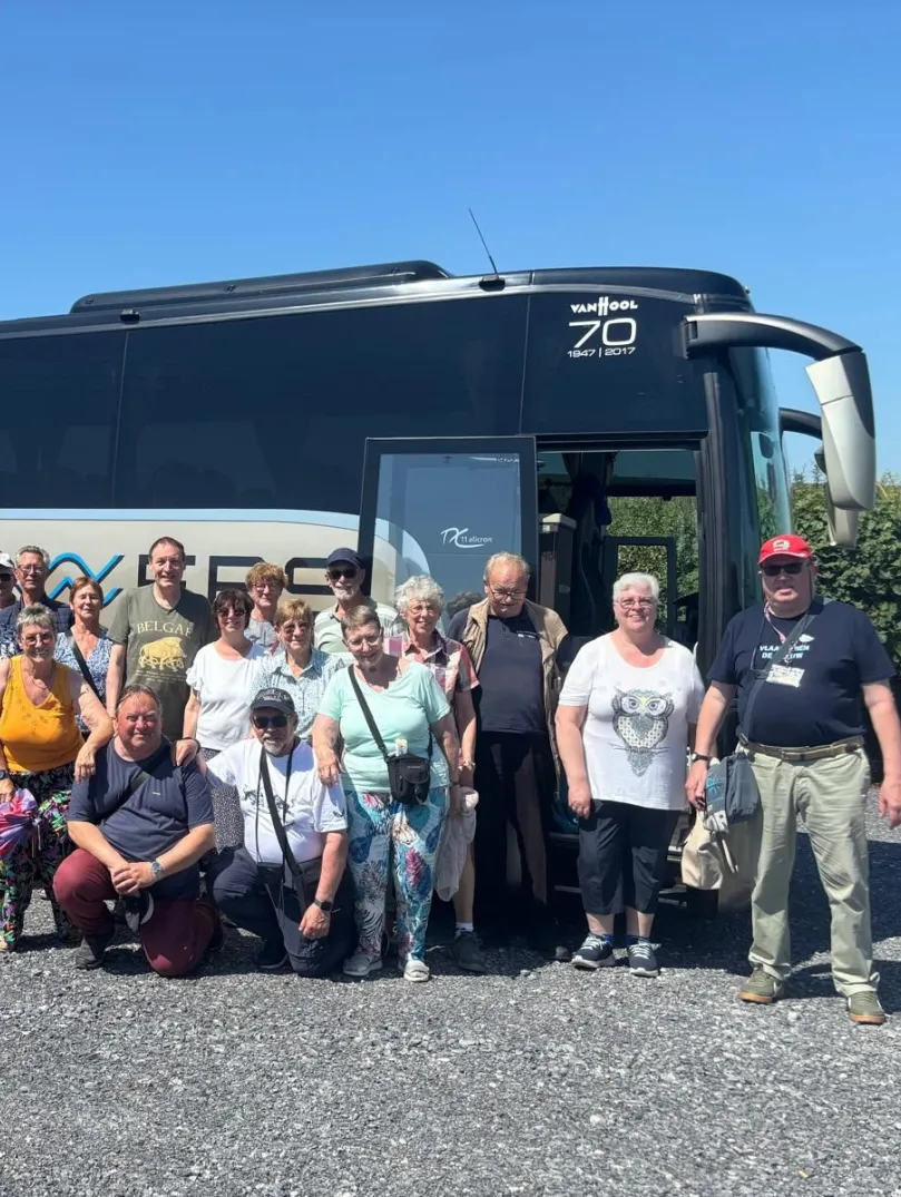 Group of people standing by a coach smiling at the camera