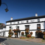 A traditional hotel adorned with flower baskets and window boxes in a town.