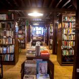 The aisle of a book shop with shelves either side full of books in Hay on Wye.