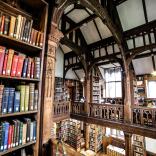 A library taken from a balcony showing shelves of books and an ornate roofspace.