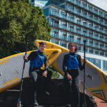 Two paddleboarders standing outside a hotel.