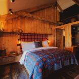 A hotel room with wooden panelling and a welsh bedspread on the bed.