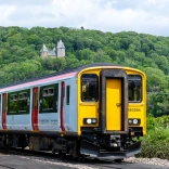 A train passing a fairytale castle on a hill.
