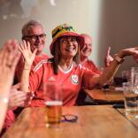 Group of people in a pub wearing Wales team football shirts.