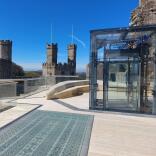 A viewing platform and glass lift inside a castle.