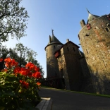Flowers in bloom next to the path of a castle entrance.