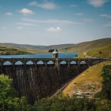 Aerial shot of a dam and a reservoir with mountainous scenery.