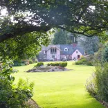 A house amongst a beautiful lawn and gardens.