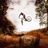 A mountain biker performing a dramatic jump in a forest