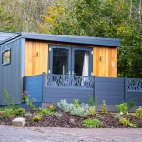 A blue wooden four berth lodge in a forest park.