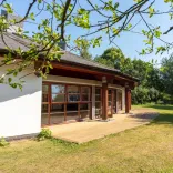 External shot of a conservatory surrounded by green trees.