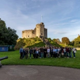 Group of people standing at the foot of a castle smiling at the camera.