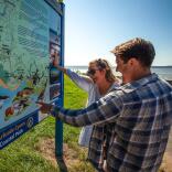 Couple looking at a tourism information sign for the Wales Coastal Path.