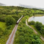 A train in the countryside passing a reservoir.