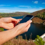 Female walker using iPhone near a reservoir.