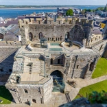 Aerial shot of a castle with the coast beyond.