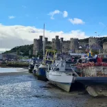 Boats on a quayside, with a castle in the background.