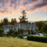 External shot of a hotel surrounded by greenery, under a dramatic sunset,