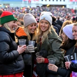 Group of ladies holding drinks and laughing, outside a sports stadium .