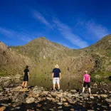 People looking at a mountain by a lake.