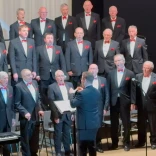 A male voice choir singing on a stage.