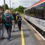 Walkers on a platform about to board a train.