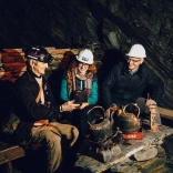A couple looking at artefacts with a tour guide in an underground mine.
