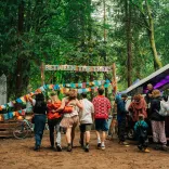 Group of people heading toward a festival in a forest.