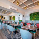 Hotel restaurant with small tables and chairs and greenery